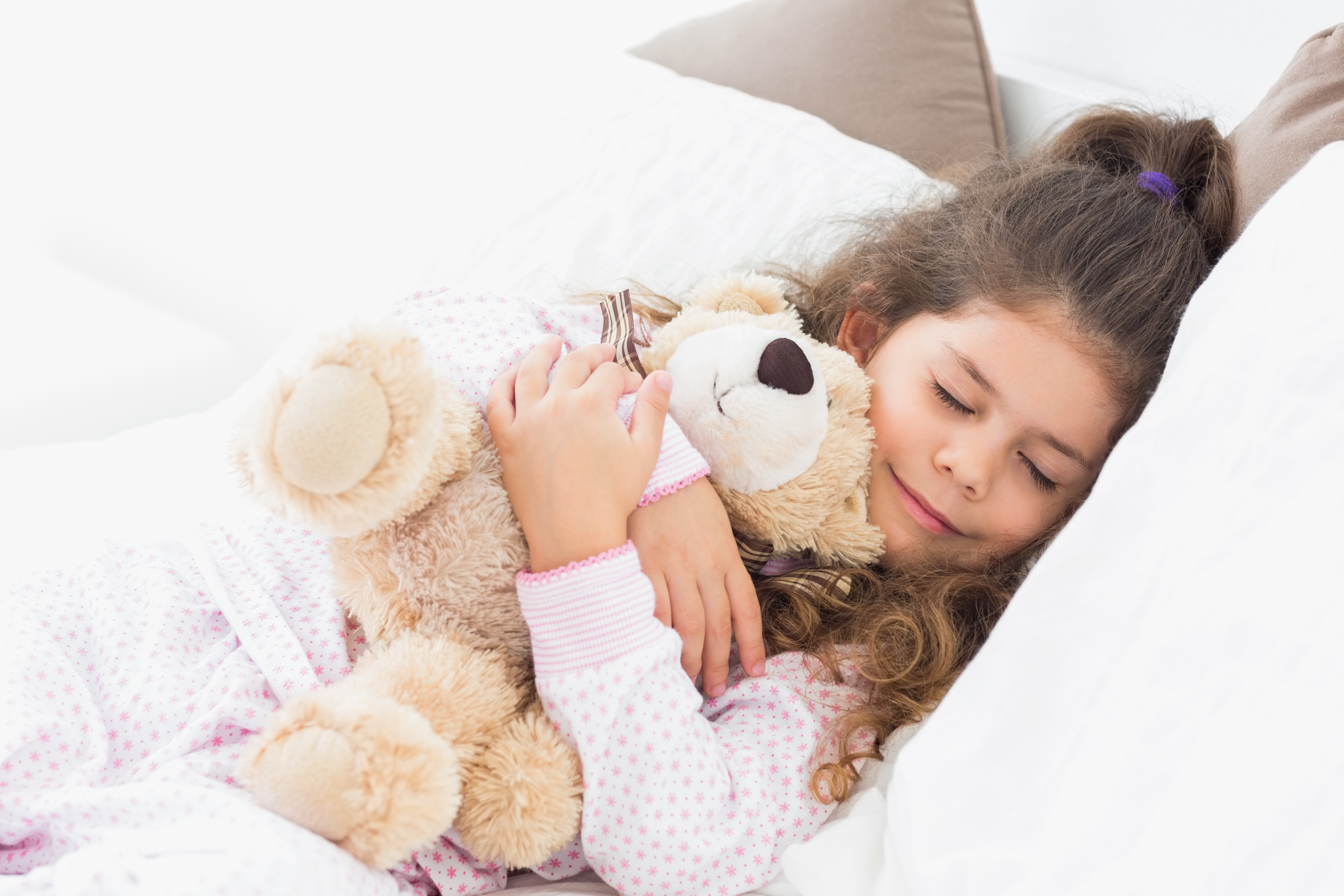Little girl asleep with her teddy bear in bed